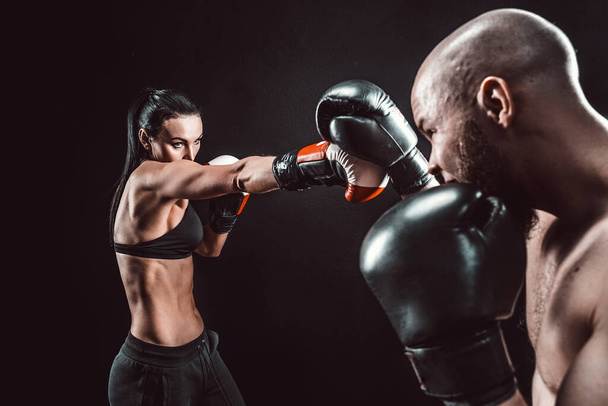Shirtless Woman exercising with trainer at boxing and self defense lesson, studio, smoke on background. Female and male fight - Fotó, kép