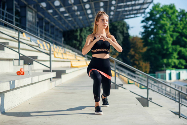 Young sporty woman doing exercises with rubber band outdoor - Foto, Imagem