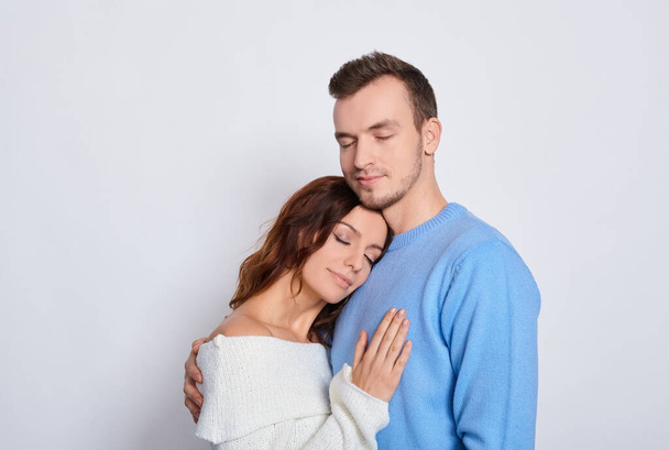 Studio shot of a head shot of a tender attractive millennial couple in love shut their eyes, romantic relationship, young wife and family husband, concept image of love and dating. Copy space. - Photo, image