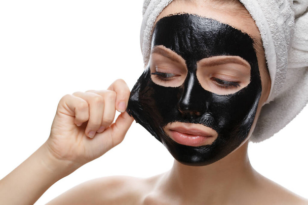 girl takes off black cosmetic mask from her face - Foto, afbeelding