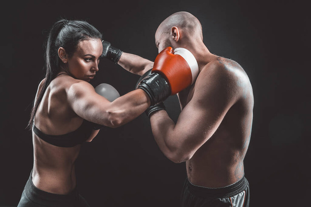 Shirtless Woman exercising with trainer at boxing and self defense lesson, studio, smoke on background. Female and male fight - Foto, Imagem