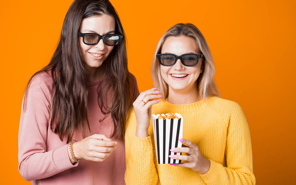 Két barát néz egy filmet vagy sorozatot, és popcornt esznek. Két fiatal női rajongó a filmért, - Fotó, kép