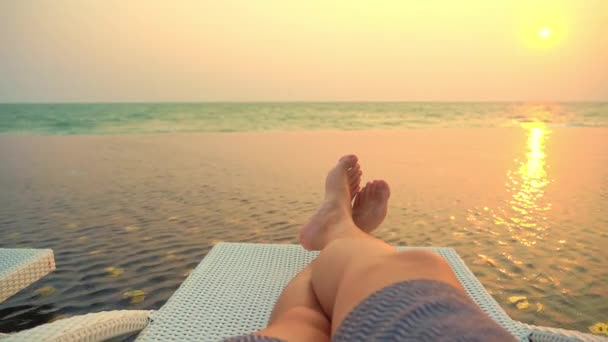 filmación recortada de las piernas del hombre relajándose en la orilla del mar - Metraje, vídeo