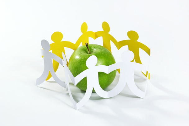κύκλο των ανθρώπων χαρτί γύρω από το πράσινο μήλο - Φωτογραφία, εικόνα