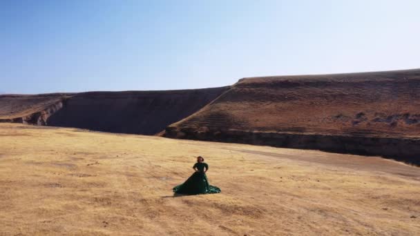 Nainen vihreässä mekossa vuorten taustalla Etelä-Kazakstanissa. Nuori nainen satu pallo puku taustalla vuoret ja keltainen aro. Kaunis tyttö pitkä mekko vuorilla
 - Materiaali, video