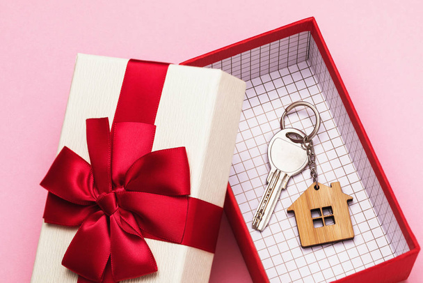 Ключ от дома в коробке на розовом фоне. Концепция подарка недвижимости
 - Фото, изображение