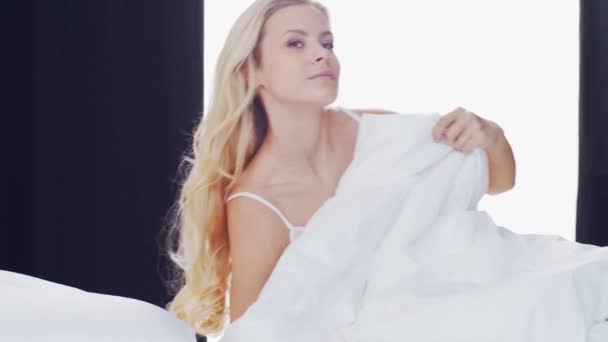 Young woman in the bed. Beautiful blond girl wakes up. Morning in the bedroom, daylight from the window. Health and rest concept. - Séquence, vidéo