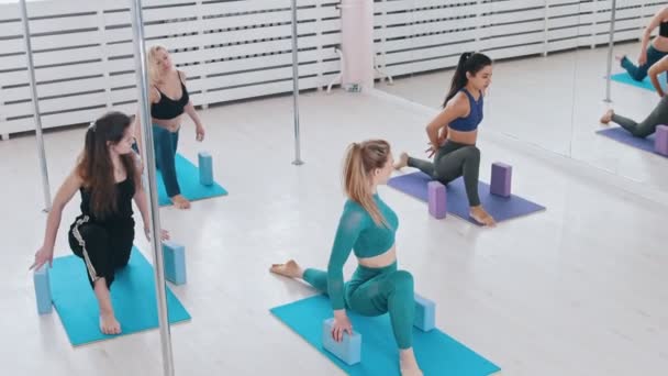 Parlak stüdyoda, elleri tuğlalı yoga minderleri üzerinde spor yapan genç kadınlar. - Video, Çekim