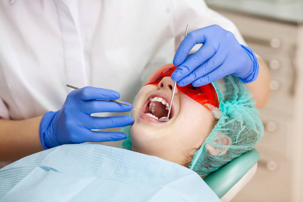 Una chica en la cita con el dentista. Inspección de la cavidad oral y los dientes en un niño
. - Foto, imagen