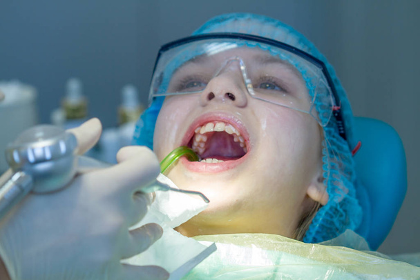 Una chica en la cita con el dentista. Inspección de la cavidad oral y los dientes en un niño
. - Foto, Imagen