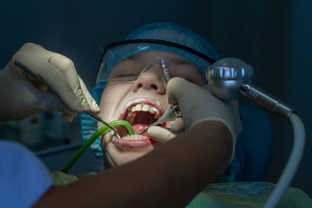 Una chica en la cita con el dentista. Inspección de la cavidad oral y los dientes en un niño
. - Foto, imagen