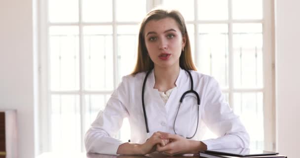 Young female doctor wear white uniform looking talking to camera - Кадри, відео