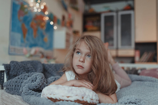 Красивая маленькая девочка лежит на подушке в виде пончика, в помещении
 - Фото, изображение