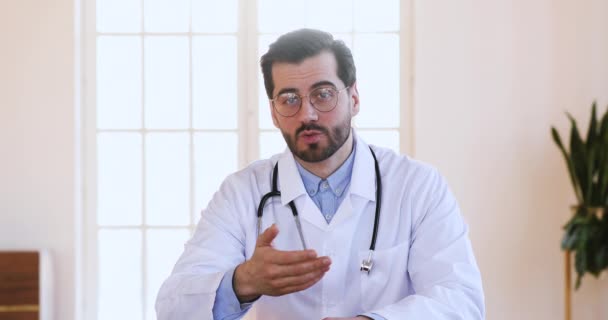 Professional male doctor speaking looking at camera make video call - Πλάνα, βίντεο
