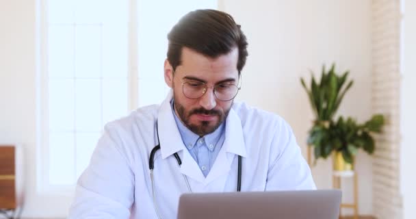 Thoughtful male doctor using laptop thinking of medical problem solution - Filmati, video