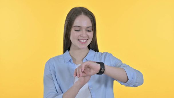 Hermosa mujer joven usando Smartwatch, fondo amarillo
 - Foto, Imagen
