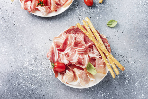 traditional italian antipasto with ham, salami and bread sticks, selective focus image - Фото, изображение