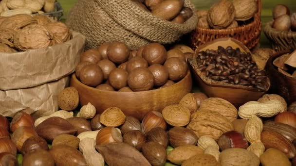 Mix ořechů. Ořechy, mandle, chilli, ořechy, arašídy, lískové oříšky jsou na zeleném dřevěném povrchu. Úchyláci. Ořechy zblízka. Detailní informace o potravinách - Záběry, video