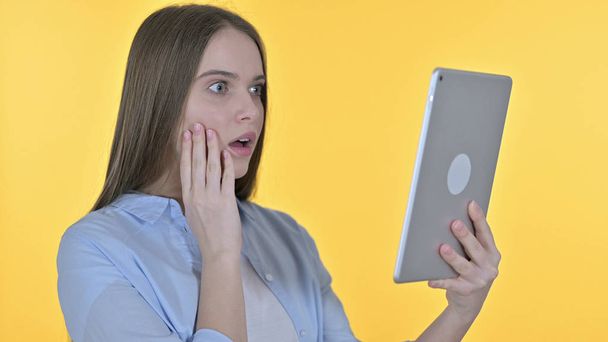 Nenucená mladá žena rozrušená ztrátou na tabletu, žluté pozadí - Fotografie, Obrázek