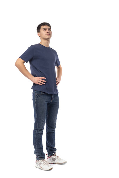 Full length portret van de jonge zeker jongen tiener van de brunette dragen van blauw shirt op een witte achtergrond in studio.  - Foto, afbeelding