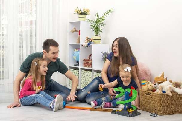 2人の小さな子供を持つ若い家族が家で一緒に時間を過ごす。家庭価値の概念。ライフスタイル。家族における男性の現代的な役割. - 写真・画像