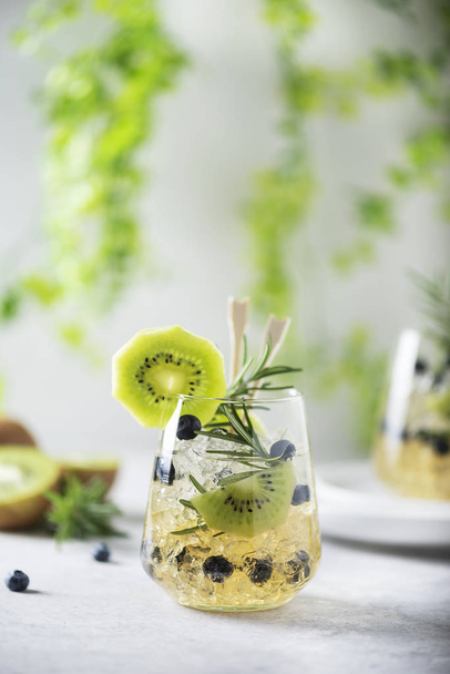 Summer cocktail with kiwi, blueberry, rosemary and ice, selective focus - Photo, Image