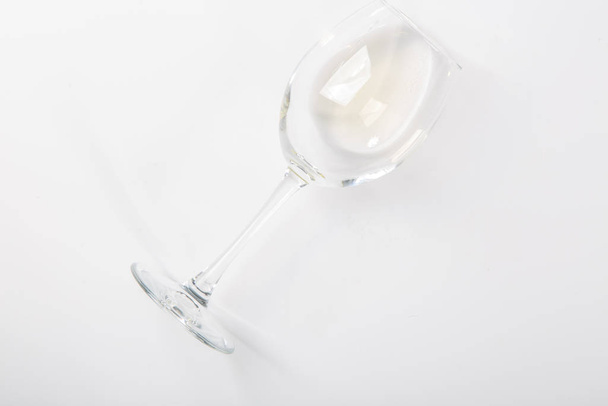 a glass of white wine lies on its side on a white background - Φωτογραφία, εικόνα