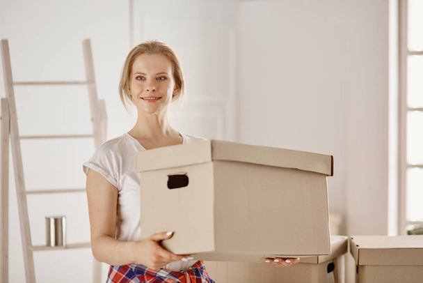 A beautiful single young woman unpacking boxes and moving into a new home - Photo, Image