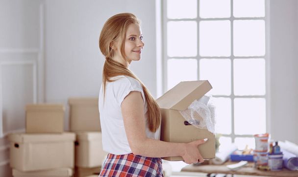 Красивая одинокая девушка распаковывает коробки и переезжает в новый дом - Фото, изображение