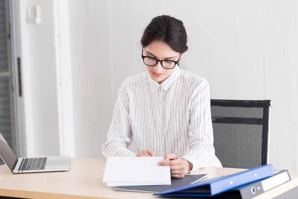 A businesswoman wearing glasses working with smiling and happiness at the office. - Photo, Image
