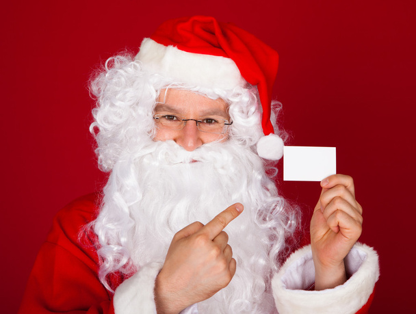 Portrait of a santa holding blank visiting card - 写真・画像