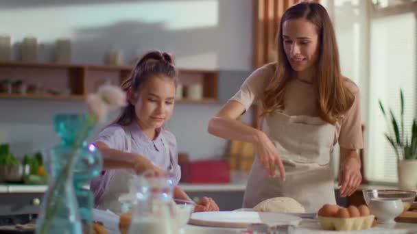 Niña y mujer rociando harina en la mesa en la cocina moderna
 - Metraje, vídeo