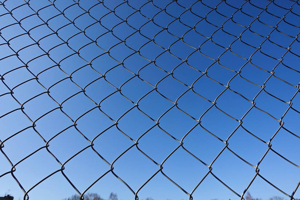 Kovová síť s modrou oblohou, železný plot na modré obloze, síťový plot, drátěný plot a pozadí modré oblohy - Fotografie, Obrázek