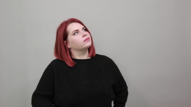 Young redhead fat lady in black sweater woman thinks, touches chin with hand - Filmmaterial, Video