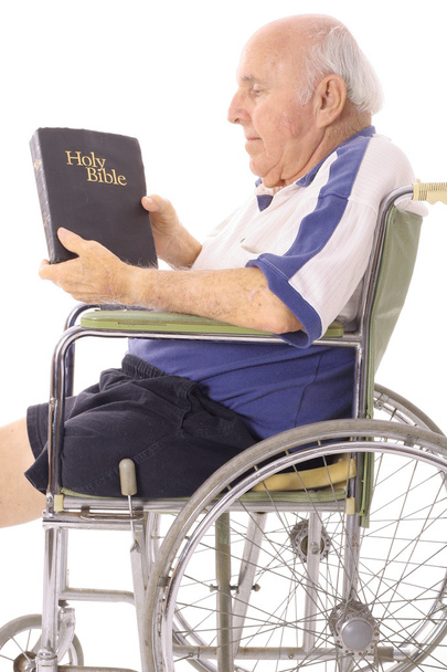 Vanha mies pyörätuolissa lukemassa Raamattua
 - Valokuva, kuva