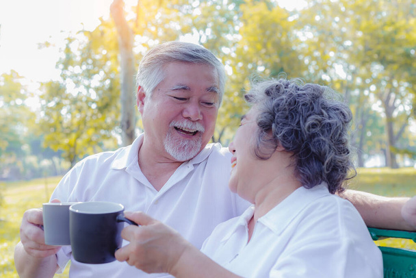 Happy life and long lived concept. Older couple is clinking cup of coffee and enjoying the drink in the morning. Handsome grandfather and beautiful grandmother are laughing and get happiness of life - Photo, Image