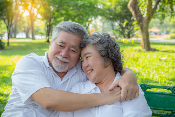 ロマンチックな年上のカップル。年配の男性や高齢のアジア人の夫がシニア妻を受け入れる。素敵な高齢者のカップルは、彼らの人生について話して、公園で笑顔の顔。老人とおばあさんはとても愛し合っている - 写真・画像