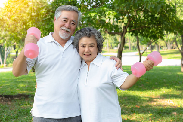 Gezond concept. Oudere echtparen hebben een goede gezondheid en zien er sterk uit omdat oudere mannen en oudere vrouwen elke dag van lichaamsbeweging of training houden. Grootvader en grootmoeder houden halter met smiley gezichten - Foto, afbeelding