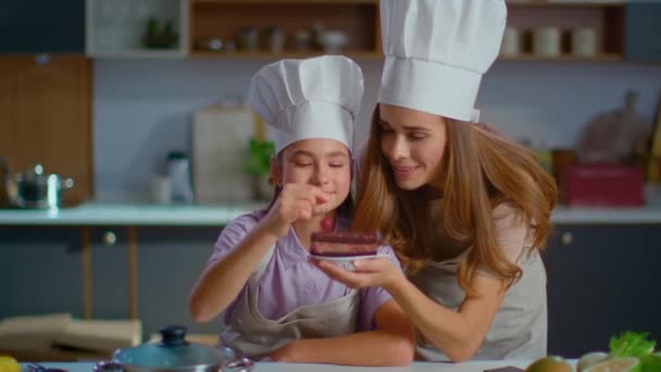Мать и дочь в шляпах украшают торт вишней на домашней кухне
 - Кадры, видео