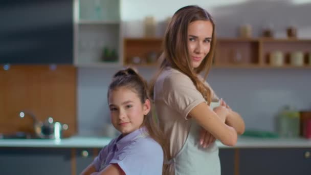 Mother and daughter in aprons crossing hands on kitchen in slow motion - Záběry, video