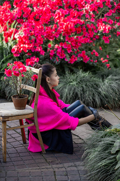Nuori tyttö istuu lattialla kasvitieteellinen puutarha ympäröi kukkivat atsaleat
 - Valokuva, kuva
