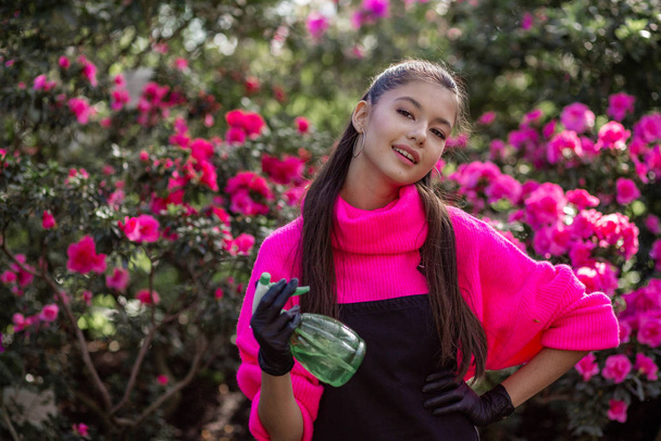 весела усміхнена дівчина позує на фото на фоні квітучого ботанічного саду
 - Фото, зображення