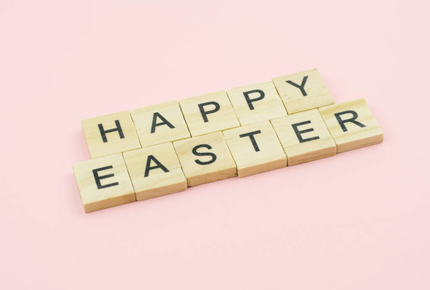 Text wooden blocks spelling the word happy easter on pink background - Fotoğraf, Görsel