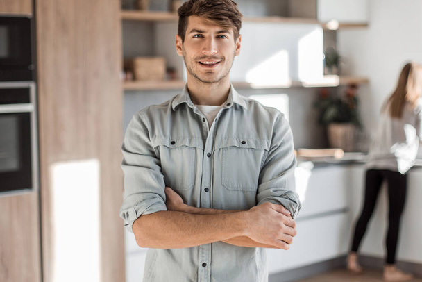 handsome young man standing in his kitchen. - 写真・画像