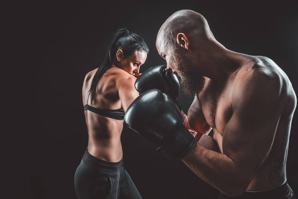 Mujer sin camisa haciendo ejercicio con entrenador en el boxeo y autodefensa lección, estudio, humo de fondo. Lucha femenina y masculina - Foto, imagen
