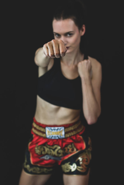 Model wearing boxing outfit smiling while throwing a punch at camera. Royalty free stock photo. - Foto, Bild