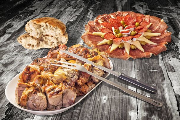 Φρεσκοψημένο χοιρινό κρέας, με σκαλιστό μαχαίρι και πιρούνι σερβιρίσματος, προσφέρεται με το πιάτο ορεκτικών αλμυρό, και αφυδατωμένο πίτα Flatbread, σε παλιό ξεπερασμένο ραγισμένο flaky Pinewood τραπέζι πικ-νικ βινιέτα φόντο. - Φωτογραφία, εικόνα