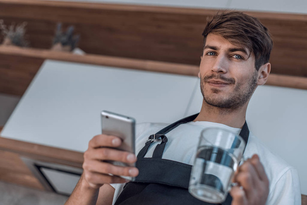 attractive young man reading a recipe on his smartphone - Fotografie, Obrázek