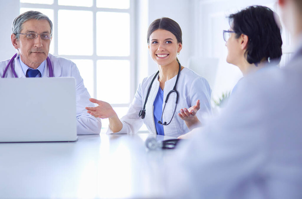 Σοβαρή ιατρική ομάδα συζητά την περίπτωση των ασθενών σε ένα φωτεινό γραφείο - Φωτογραφία, εικόνα