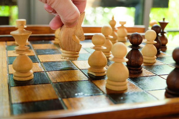 Άνδρες χέρι κατέχουν και κινείται άλογο σκάκι στο διοικητικό συμβούλιο για να ανταγωνιστεί με τον αντίπαλο. Στρατηγικός σχεδιασμός επιτραπέζιων παιχνιδιών σχετίζονται με τις επιχειρήσεις, Εταιρική δραστηριότητα. Επιτυχής έννοια, διαχείριση και λήψη αποφάσεων. - Φωτογραφία, εικόνα